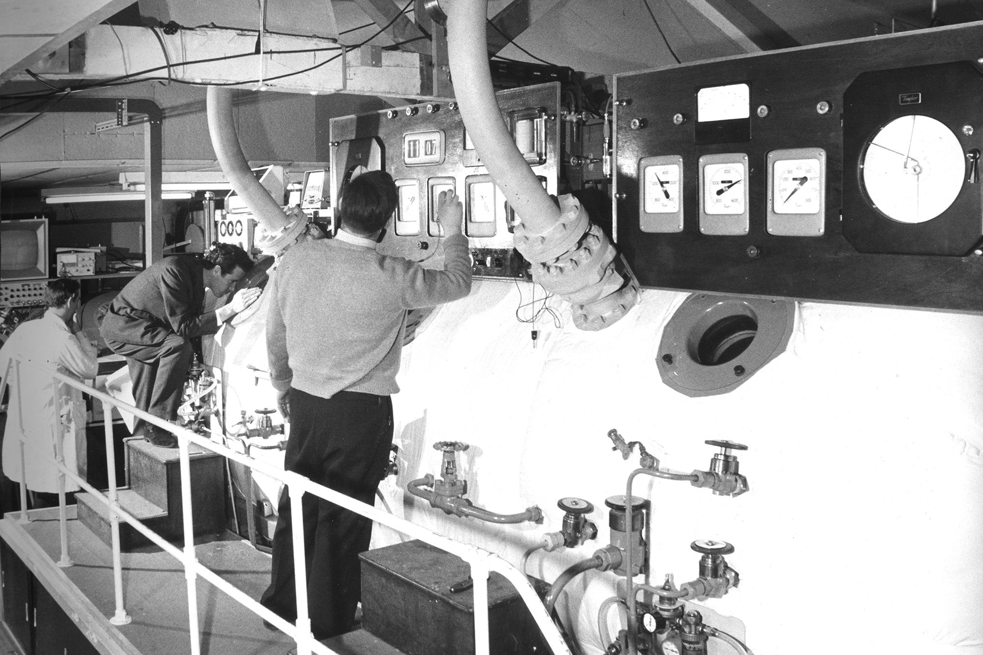 Scientific Diving - Old black and white photograph shows scientists examining a decompression chamber