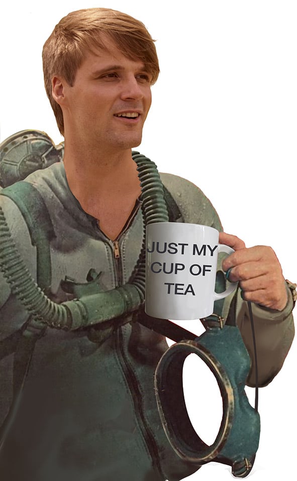 Diver wearing 1960s sports diving equipment holding a mug with 'Just my cup of tea' written on it.
