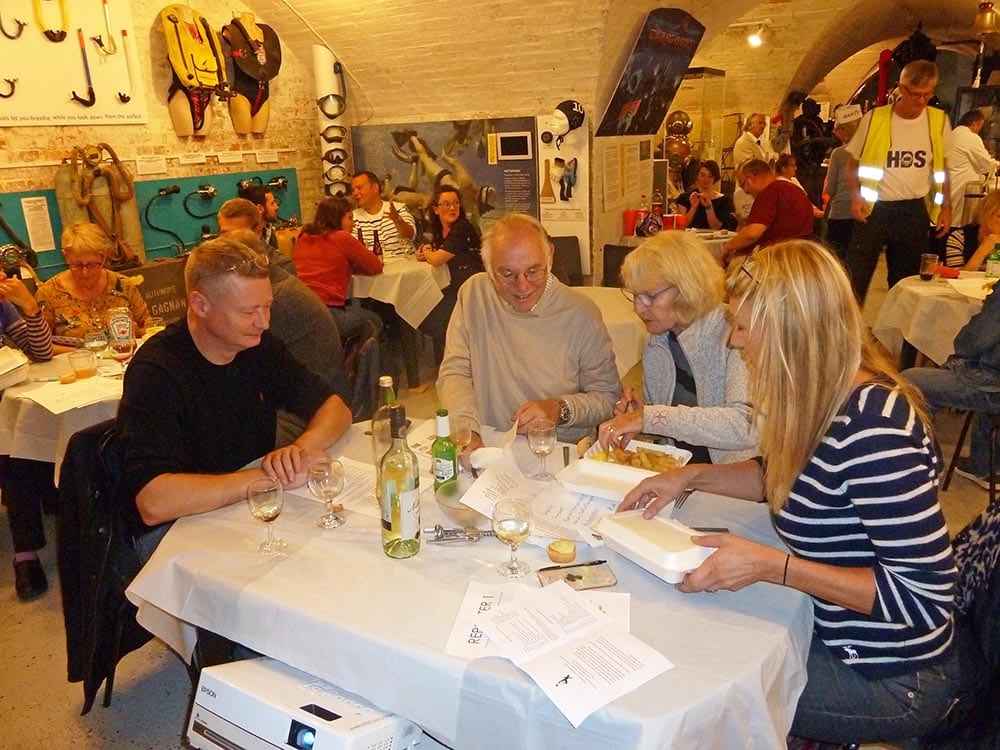 Interior of the museum with guests seated at tables eating a fish and chip supper