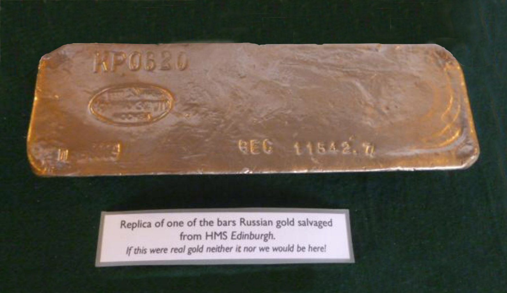 Rectangular bar of gold with Russian markings on a green baize background