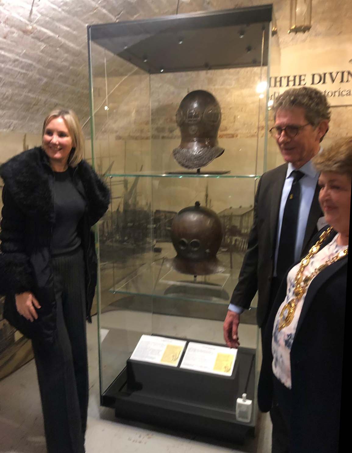 Caroline Dineage MP, with Kevin Casey (Museum Director) and the Lady Mayor of Gosport, Diane Furlong standing around the display cabinet containing the Deane and James helmets.