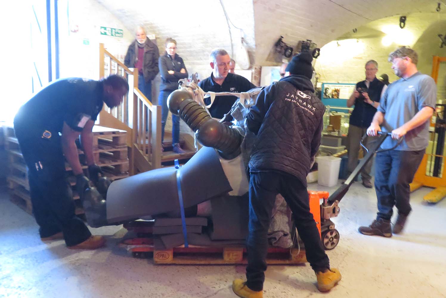 Jim suit on its back on the floor of the museum being pulled into position to be raised