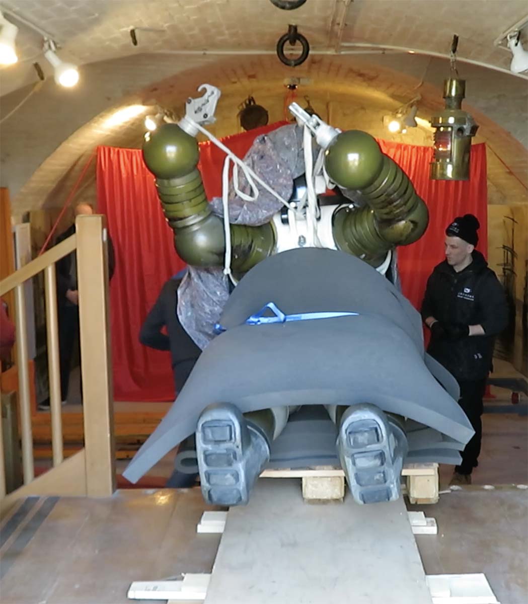 Jim suit lying on its back and draped with blankets being drawn into the front door of the museum