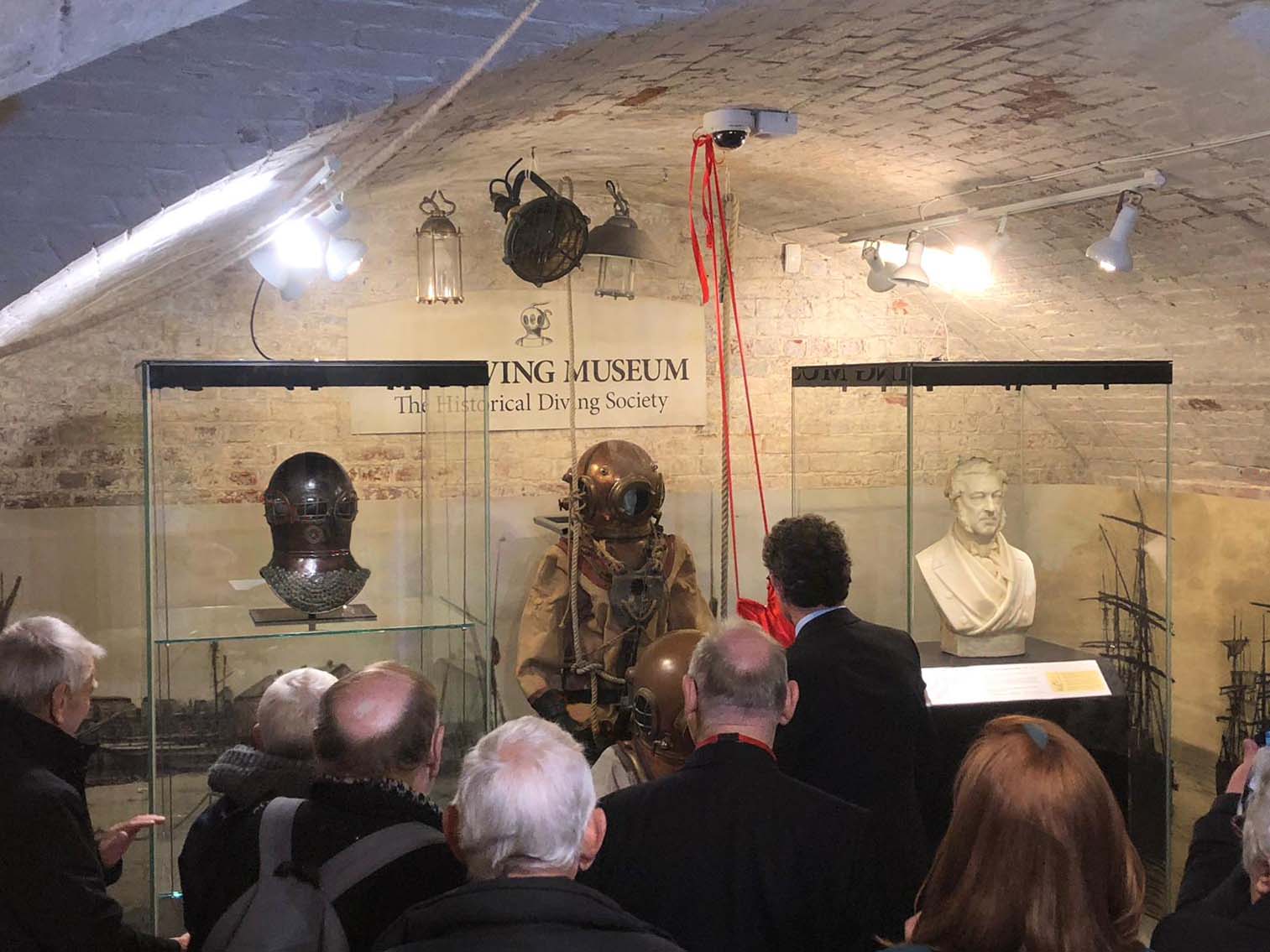 View of the new exhibits in their glass display cases. Backs of the guests in the foreground.