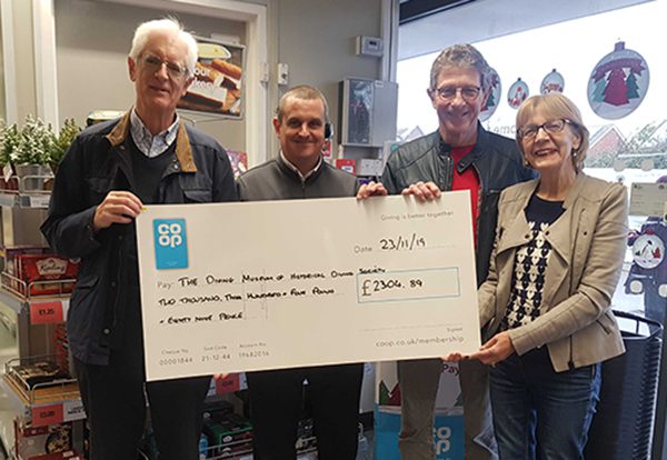 3 museum volunteers with the manager of the Co-op Privett Road Store in Gosport holding a large cheque.