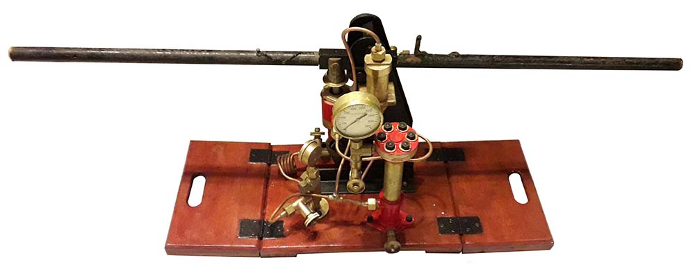 A cylinder pump with two long handles mounted on a wooden board with carrying handles cut into either end of the board.