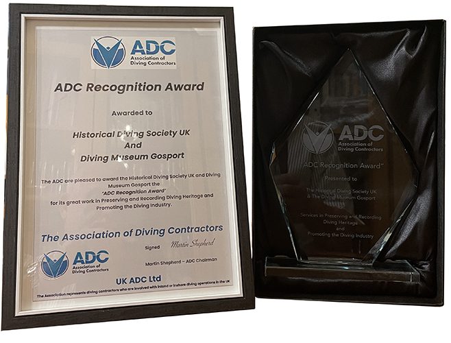 A framed certificate and engraved glass trophy in a black satin-lined presentation box.